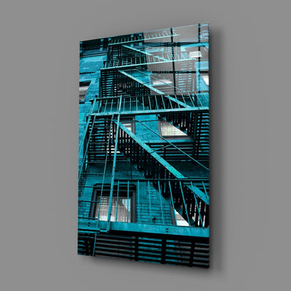 Turquoise metal fire escape stairs on brick building displayed as angled glass wall art mounted on gray background.