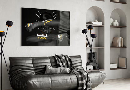 Modern living room with black leather sofa displaying Native American glass wall art featuring yellow geometric patterns and grayscale imagery above it.
