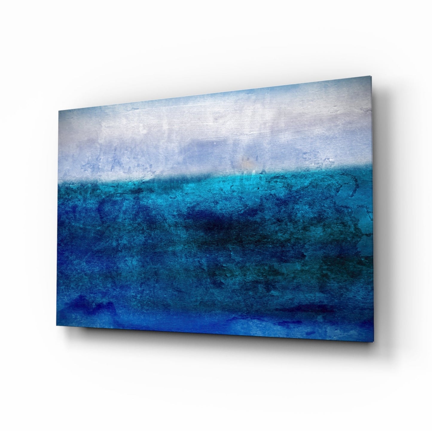 Glass wall art featuring a layered ocean scene with white sky transitioning through turquoise to deep blue water, displayed at an angle.
