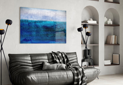 Blue and white abstract glass wall art hanging above a dark leather sofa in a modern living room interior.