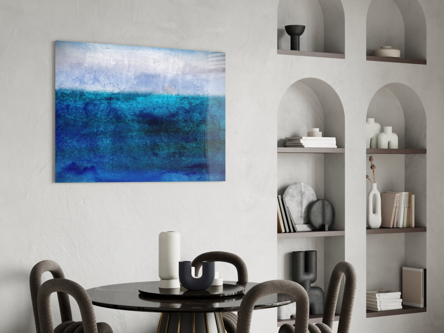 Blue gradient glass wall art depicting layered ocean tones displayed above a round black dining table.