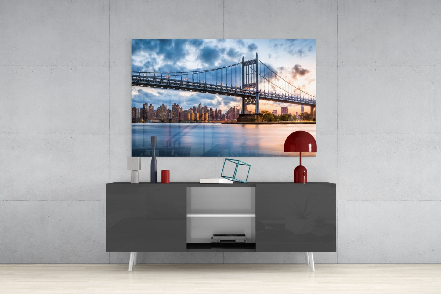 Astoria Park Glass Wall Art mounted above dark gray media console, showing Manhattan Bridge photograph with red decorative accessories on white wall.