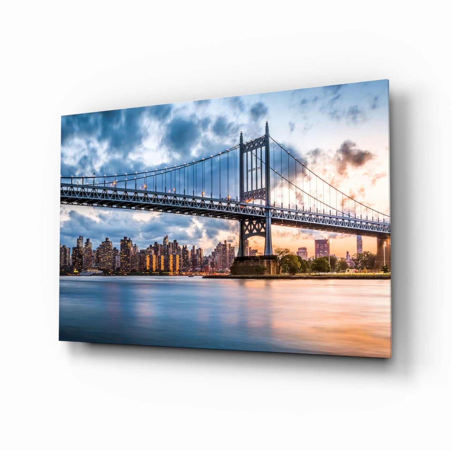 Queensboro Bridge spanning East River at sunset with Manhattan skyline illuminated in background, displayed as glass wall art on white wall.