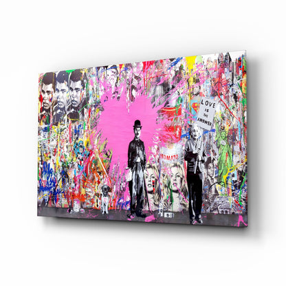 Angled view of colorful glass wall art featuring black and white figures overlaid on vibrant pink and multi-colored graffiti-style background with "Love is the Answer" text.