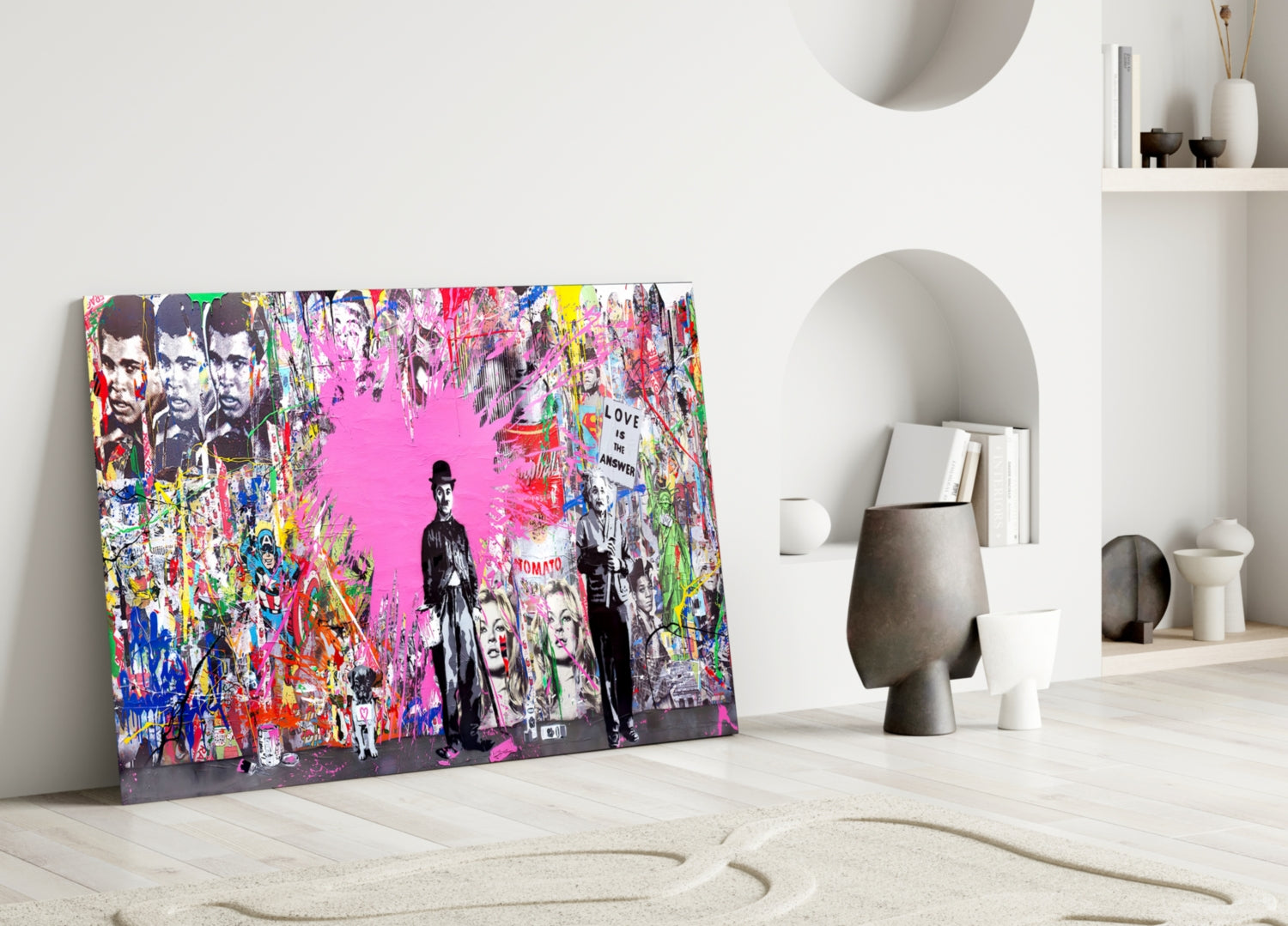 Colorful pop art glass wall panel leaning against white wall in minimalist interior, featuring vibrant graffiti-style imagery with pink background and text reading "Love is the Answer.