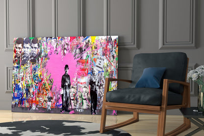 Colorful pop art glass wall panel featuring silhouetted figures and portraits on vibrant pink background, displayed in modern living room with wooden chair.