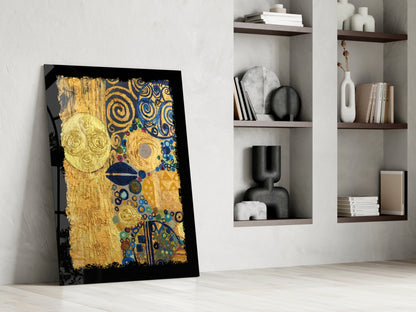 Gold abstract glass wall art with blue and golden swirls leaning against white wall next to shelving unit.