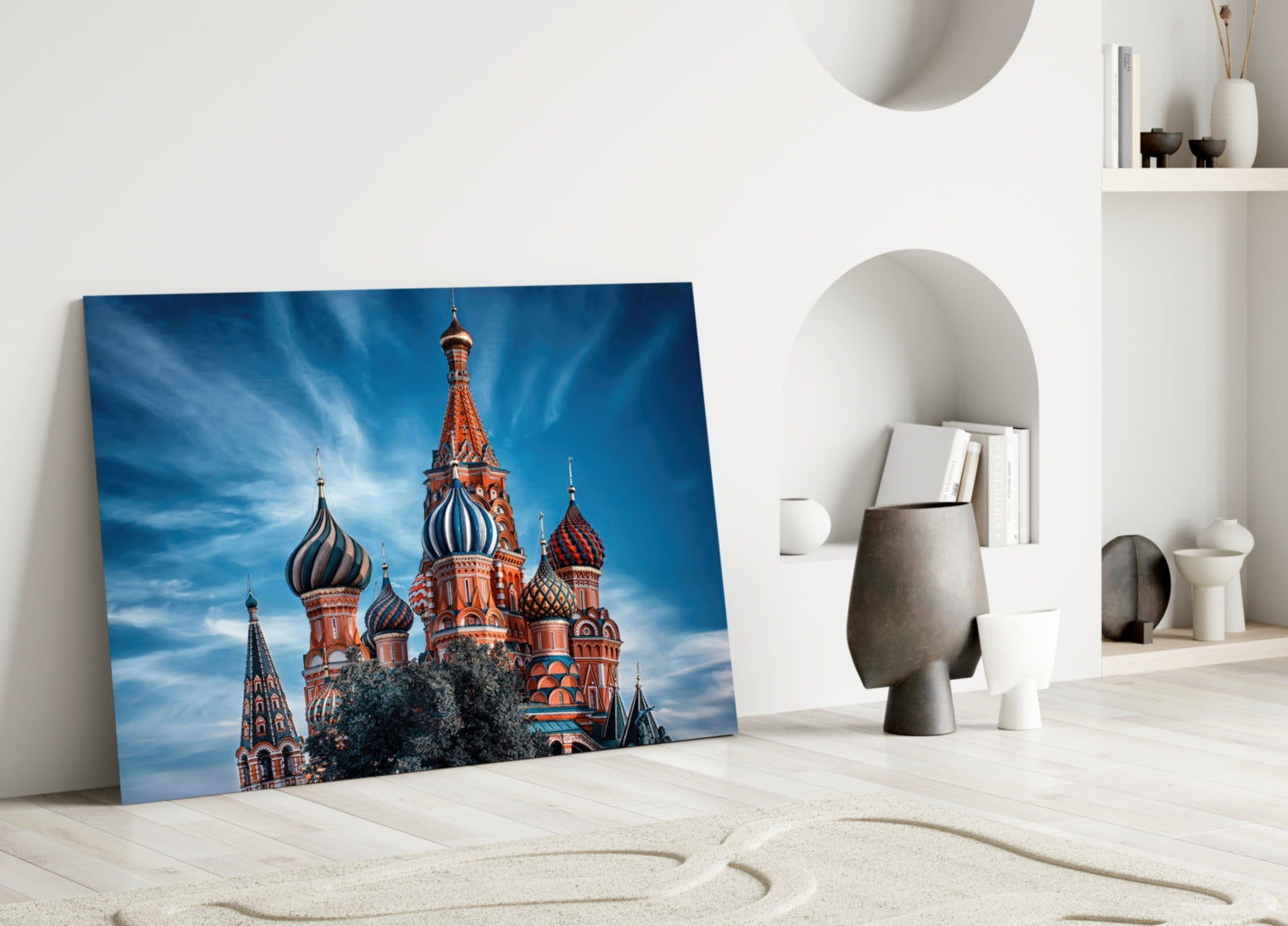 St. Basil's Cathedral glass wall art leaning against white wall in minimalist room with sand and decorative objects.