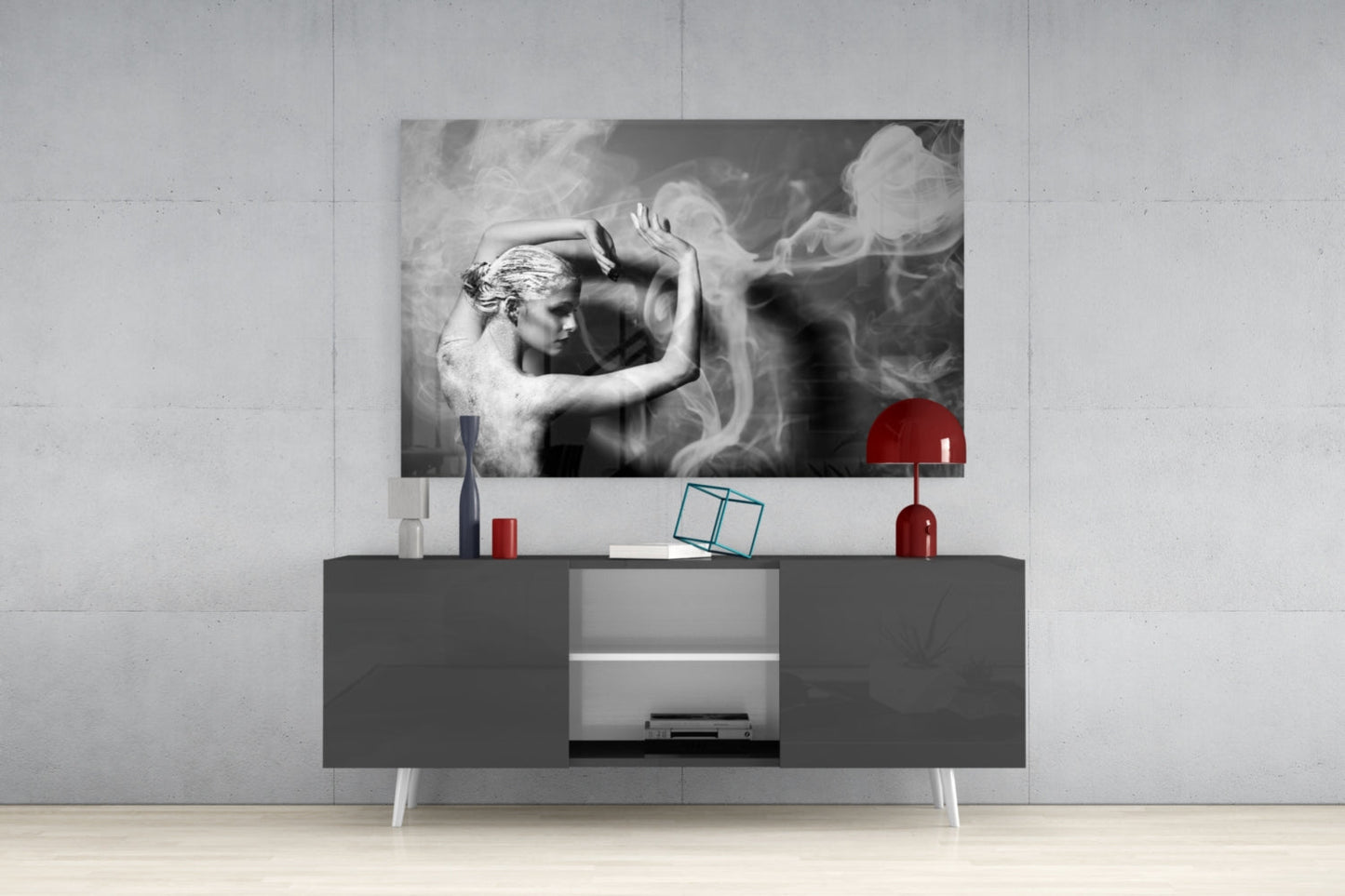 Black and white glass wall art depicting a classical figure with flowing smoke effects, displayed above a dark media console with red decorative accessories.