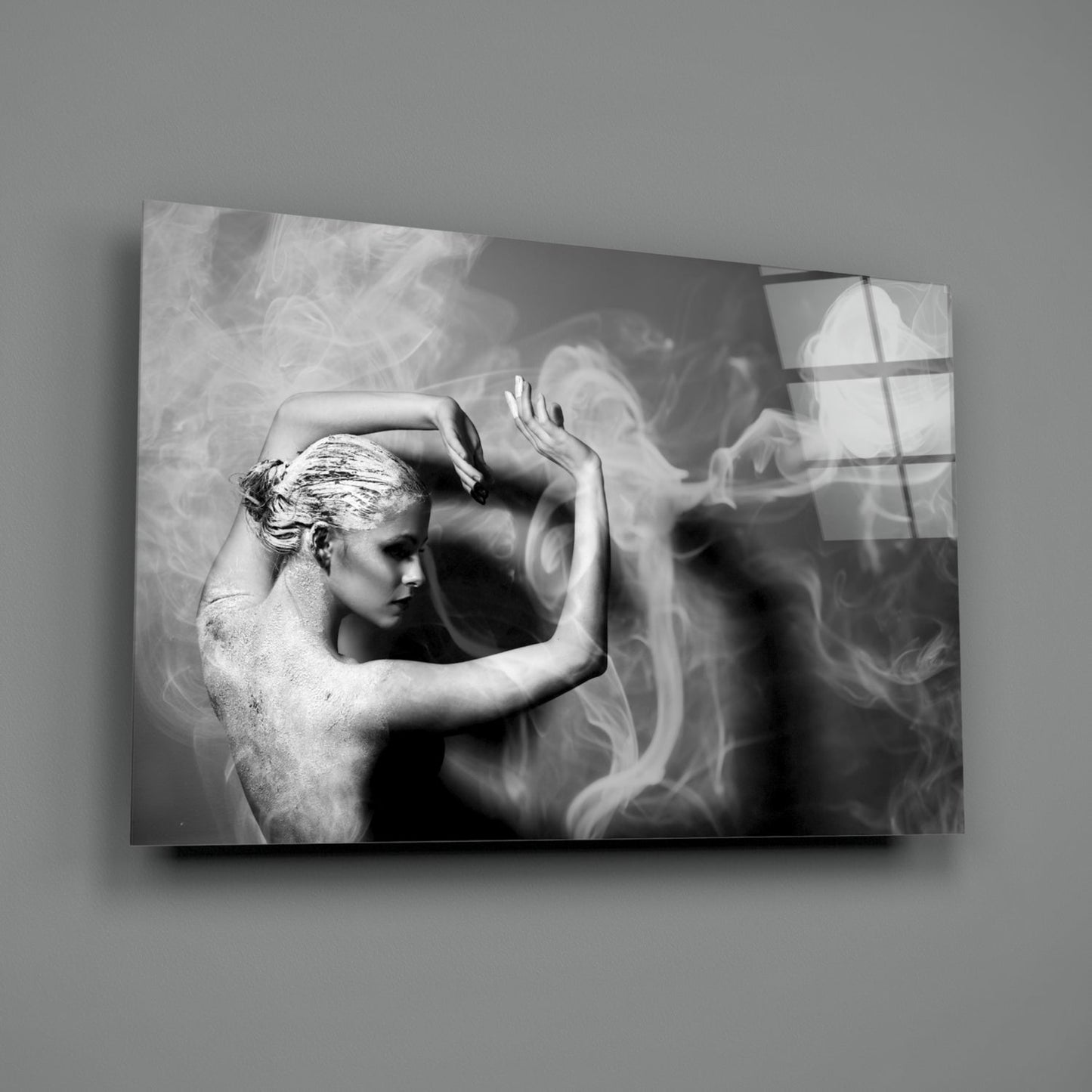 Black and white glass wall art depicting a shirtless figure with hands raised to head, surrounded by swirling smoke effects, mounted on gray wall.