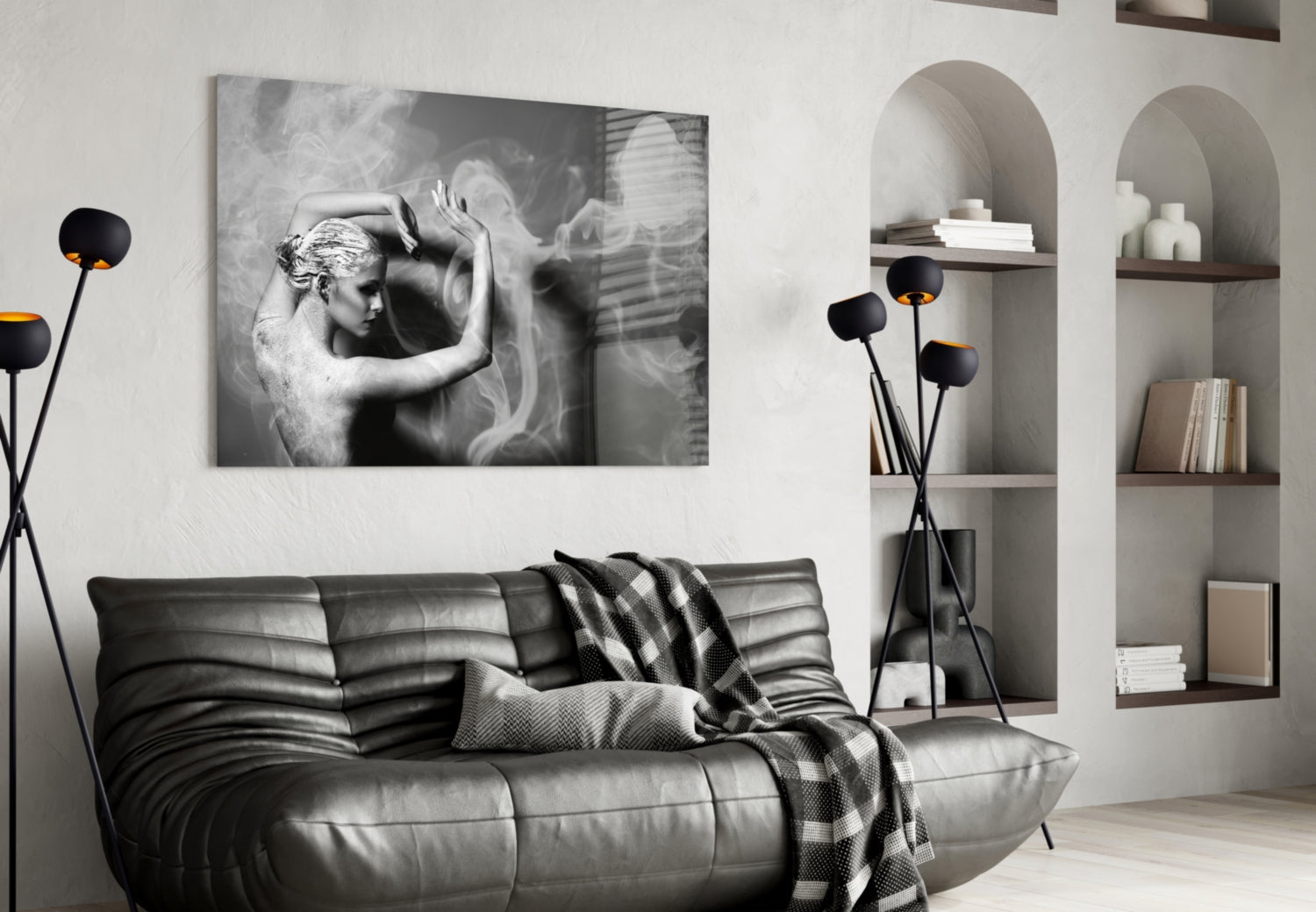 Black and white glass wall art featuring a classical figure with raised arms displayed above a dark leather sofa in a minimalist interior.