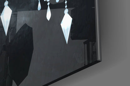 Illuminated white geometric pendant shapes hanging from chains against a dark wall display.