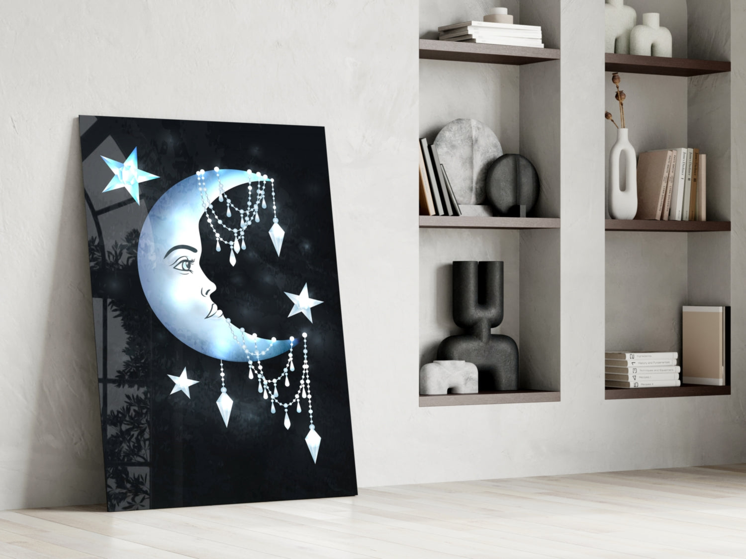 Glass wall art leaning against white wall displays blue moon face with stars and dangling crystal details beside open shelving.