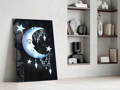 Glass wall art leaning against white wall displays blue moon face with stars and dangling crystal details beside open shelving.