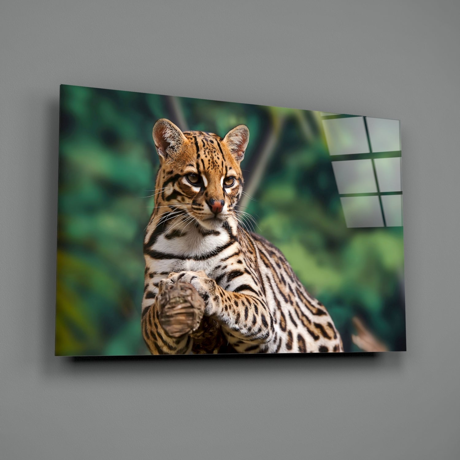 A cheetah's head and upper body displayed on a glass wall panel with green foliage background, shown at an angled perspective against a gray wall.