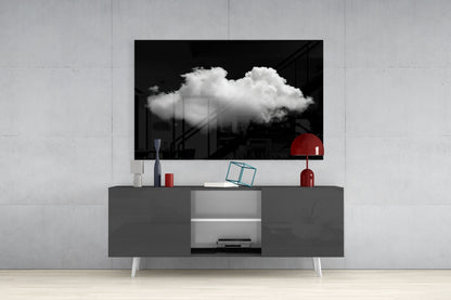 Black and white cloud glass wall art displayed above gray media console with red lamp and decorative objects in modern interior setting.