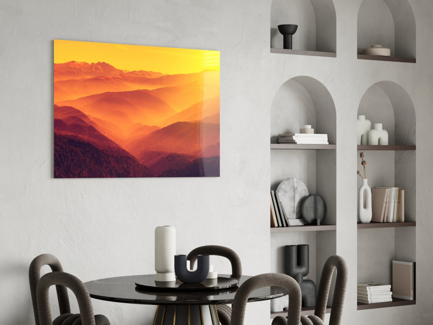 Warm Landscape Glass Wall Art displaying a golden sunset over layered mountains, hung above a black dining table in a modern interior.
