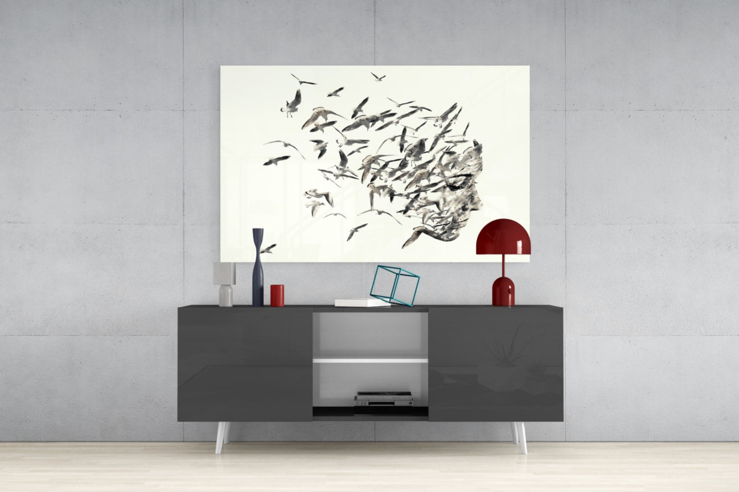 Modern living room display with glass wall art featuring black birds dispersing from textured head silhouette above dark console table with red lamp.