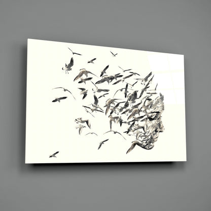 Glass wall art panel displaying a monochromatic illustration of birds flying away from a textured human head profile against a white background.
