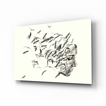 Glass wall art displaying a profile silhouette filled with flying birds in black and gray ink on cream background.