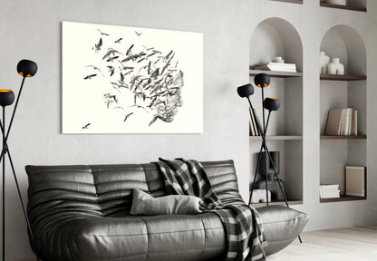 Modern living room with black leather sofa displaying horizontal glass wall art featuring birds dispersing from textured head silhouette.