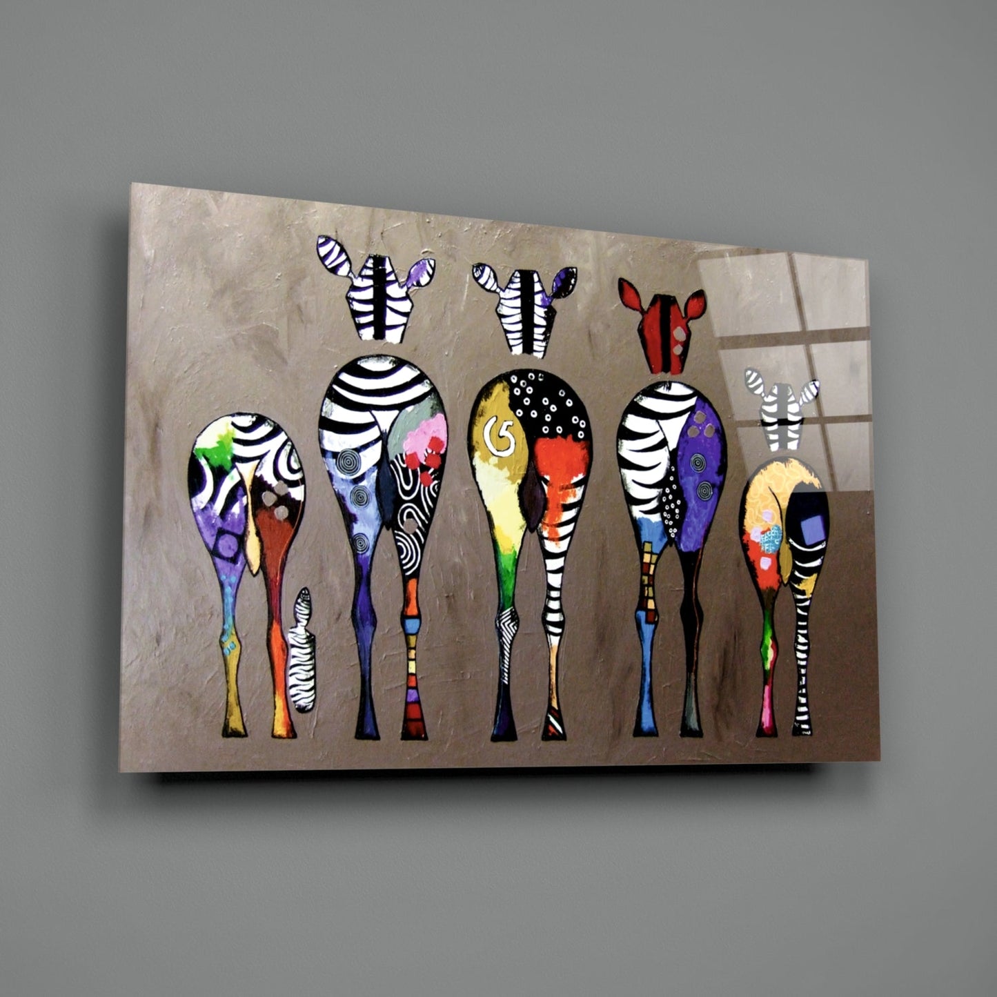 Glass wall art featuring nine stylized zebras with striped bodies and colorful patterned legs displayed on a beige textured background.
