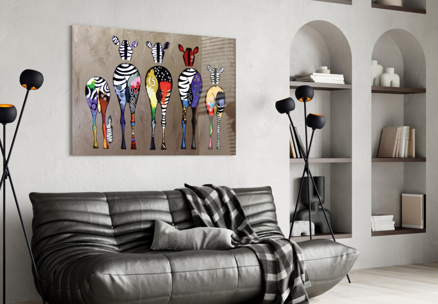 Colorful Zebras glass wall art displayed above a black leather sofa in a modern living room with arched shelving and decorative floor lamps.
