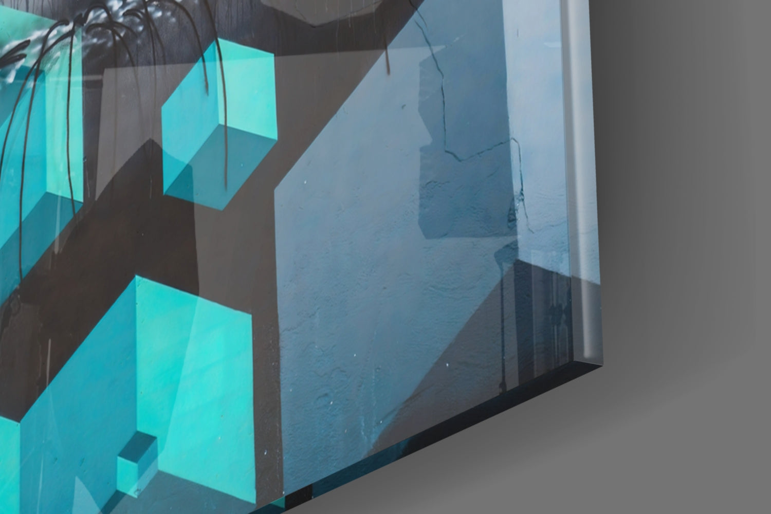 Turquoise geometric glass wall art mounted on textured wall, photographed at angle showing three-dimensional cube design and light reflections.