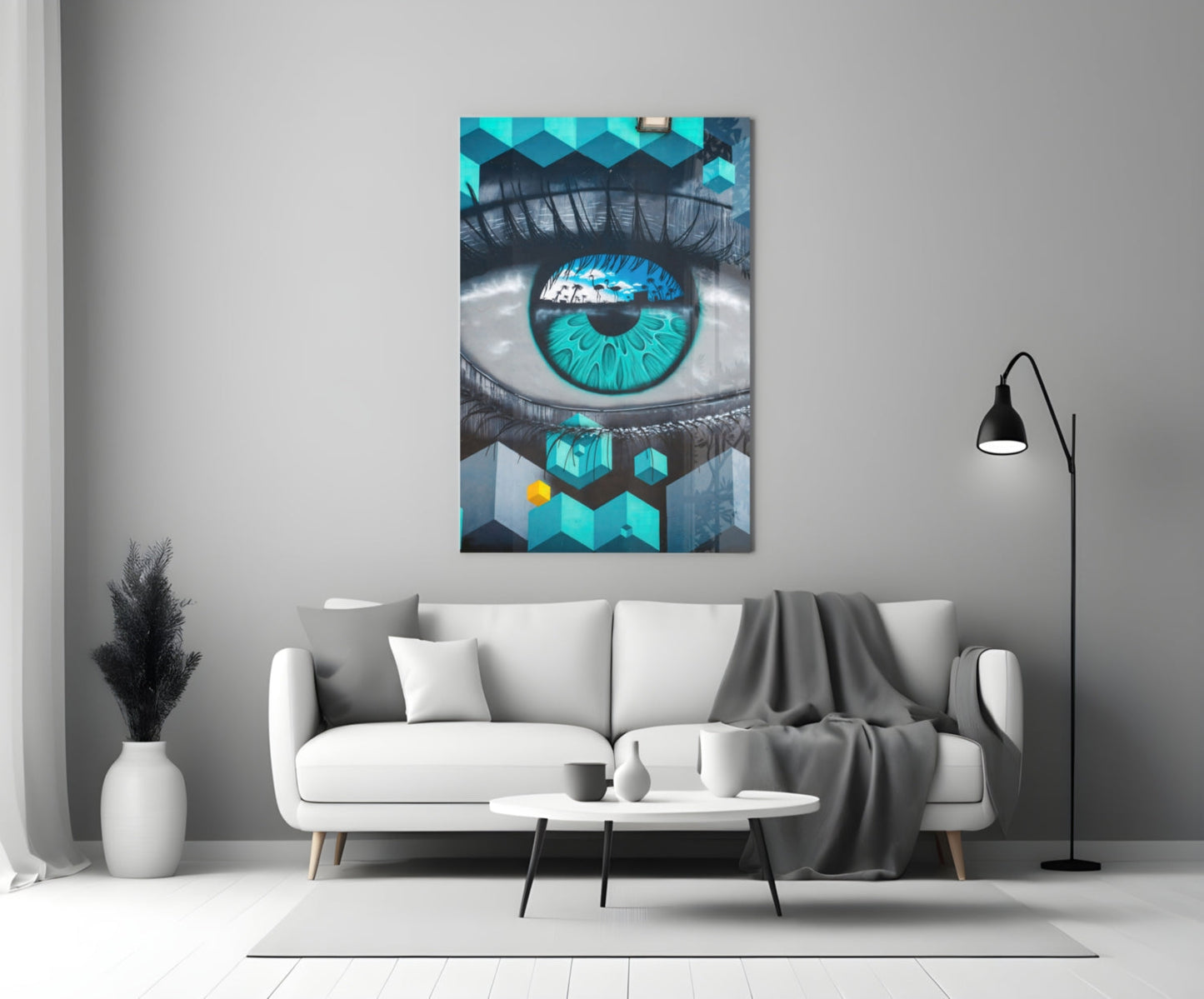 Turquoise and black eye artwork displayed on white living room wall above cream sofa with floor lamp.