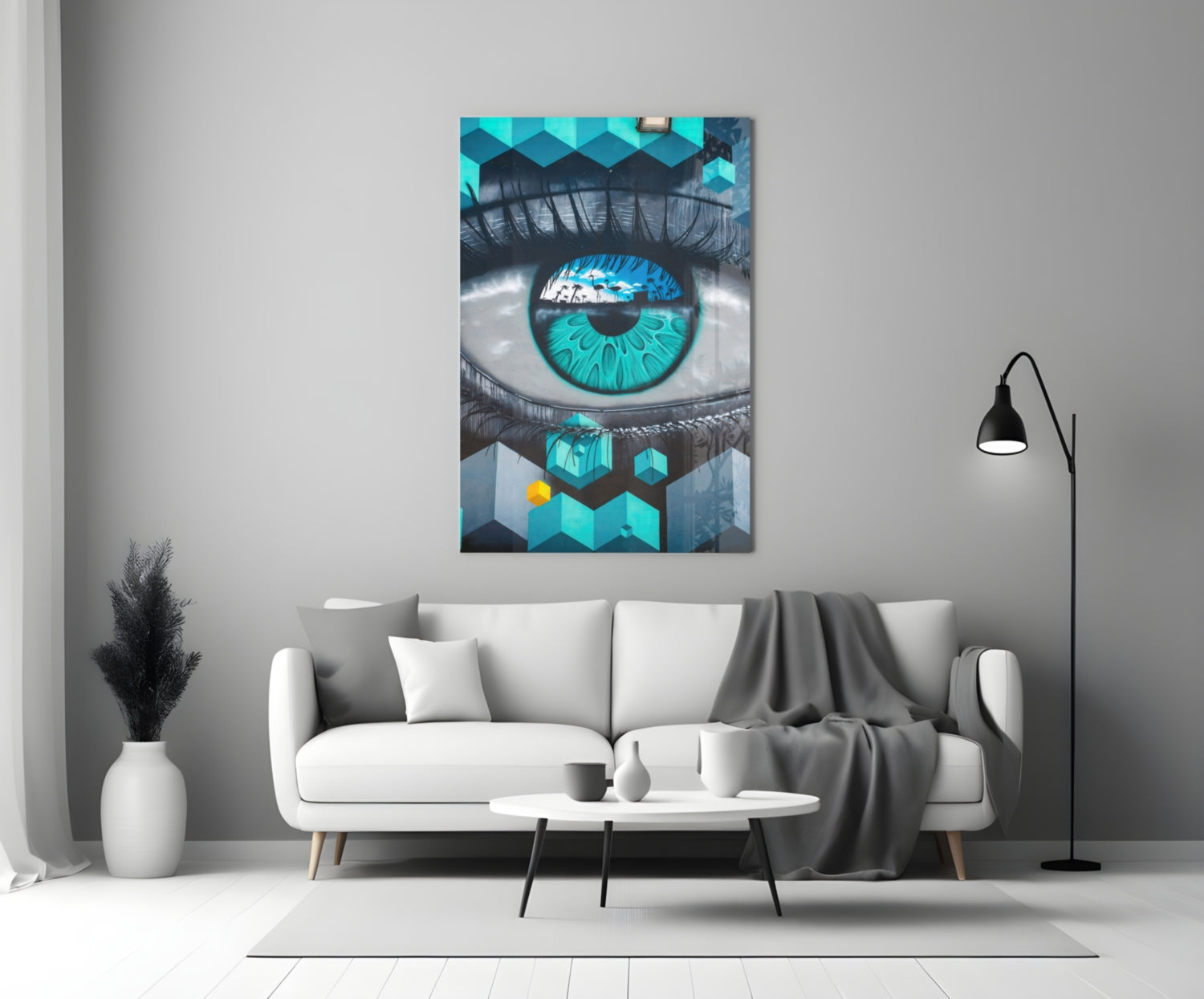 Turquoise and black eye artwork displayed on white living room wall above cream sofa with floor lamp.
