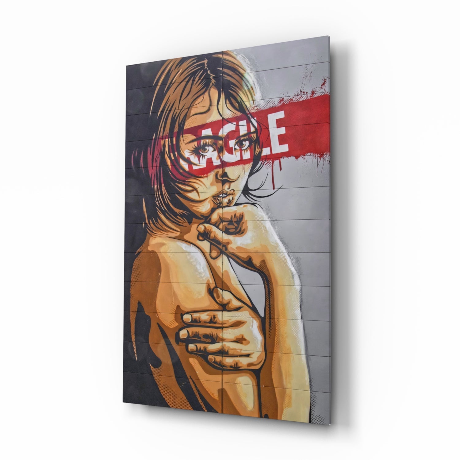 Angled perspective of glass wall art featuring portrait illustration with orange tones and red "RAGE" text overlay on gray background.