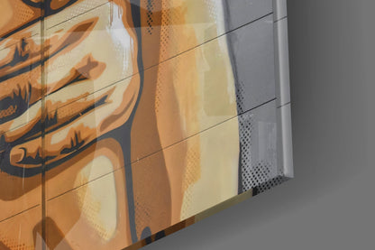 Close-up angled view of glass wall art with orange abstract design and dark blue accents on cream background, showing edge detail and gray wall.