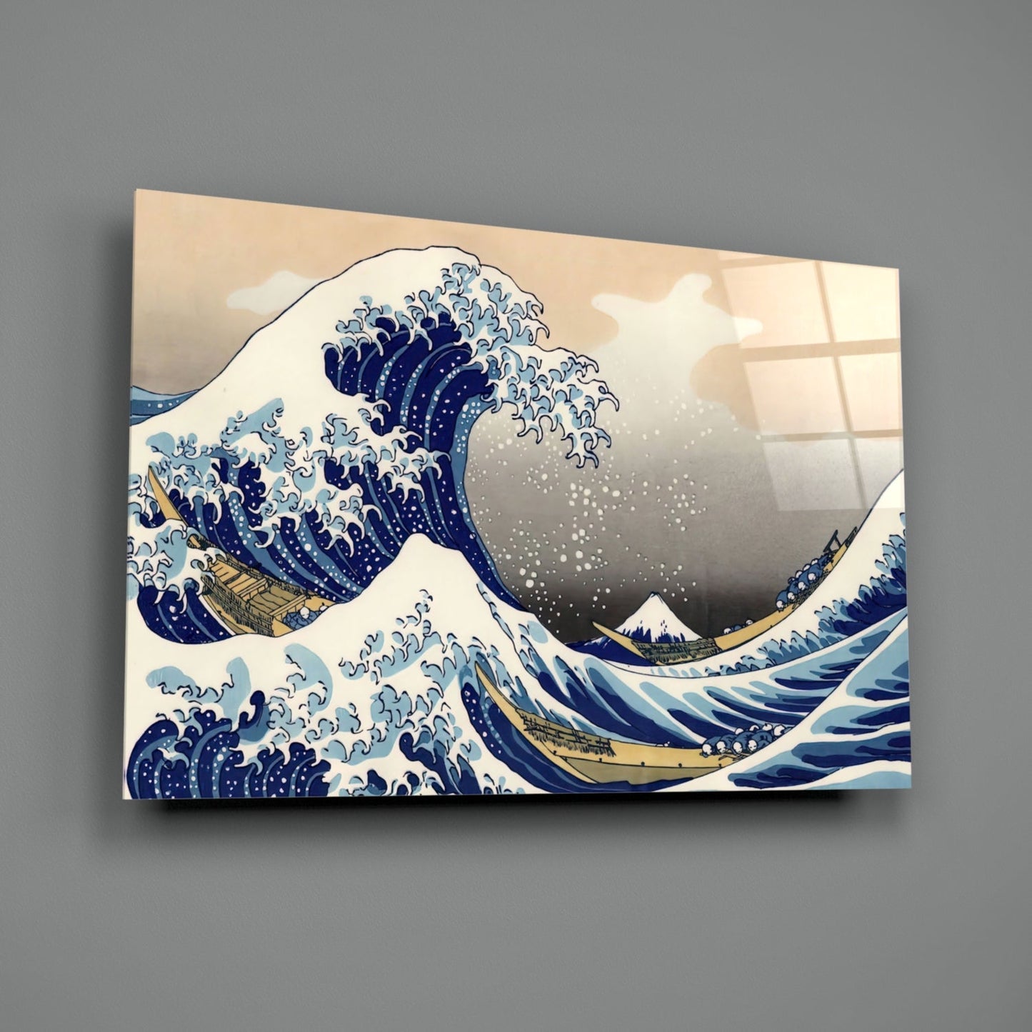 Glass wall art displaying Hokusai's Great Wave print in blue, white, and tan, mounted on gray wall at angle.