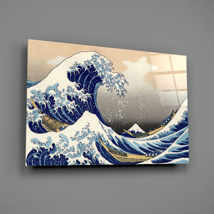 Glass wall art displaying Hokusai's Great Wave print in blue, white, and tan, mounted on gray wall at angle.