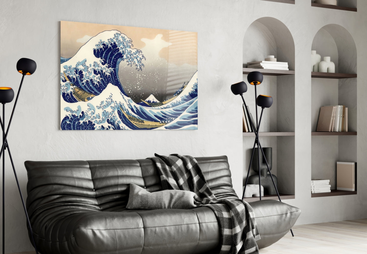 Glass wall art depicting Hokusai's Great Wave in blue and gold tones, displayed above a black leather sofa in a modern living room.