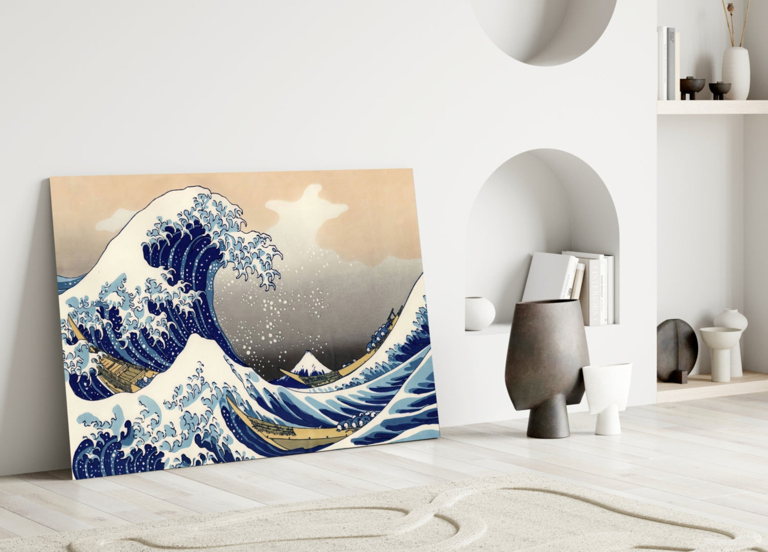 Glass wall art displaying The Great Wave in blue and cream tones, leaning against white wall beside modern sculptural decor.