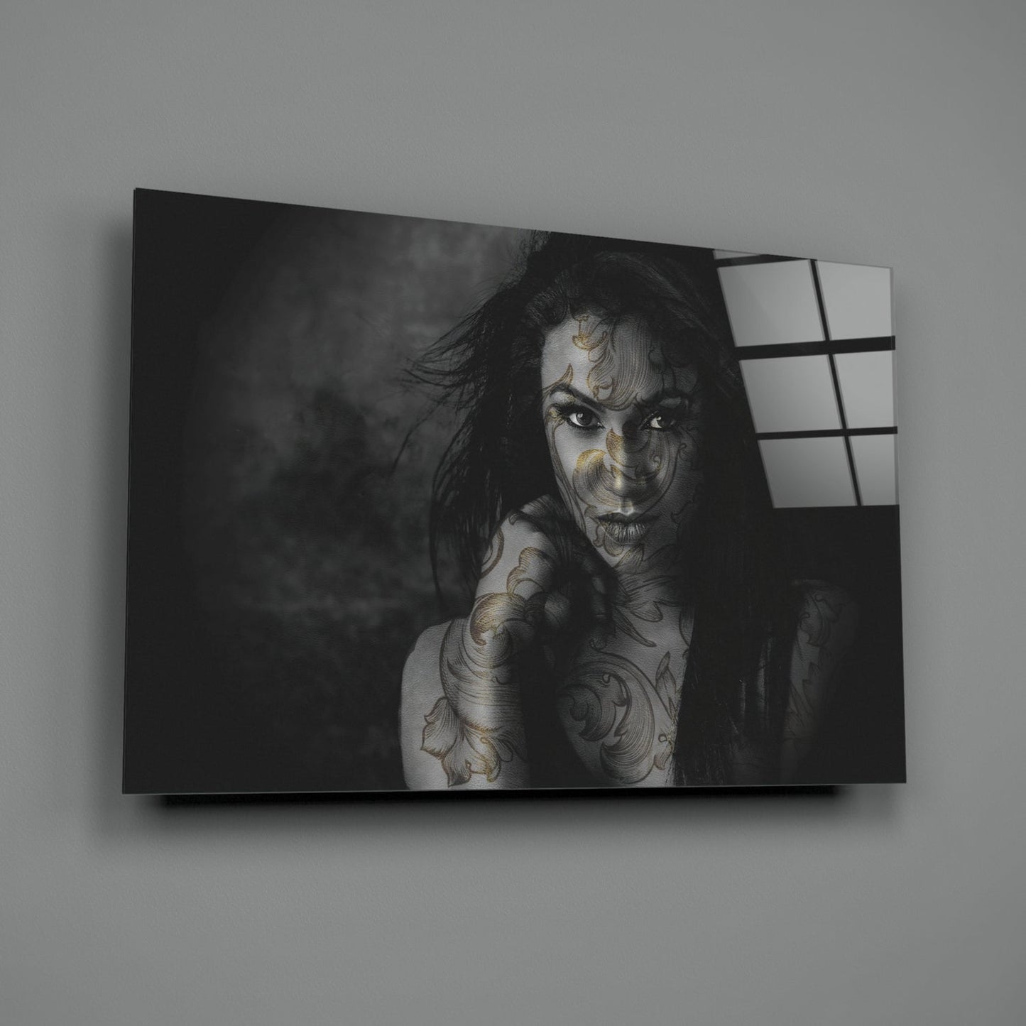 Black and white portrait of tattooed woman on glass wall art panel with window grid reflection on right side.