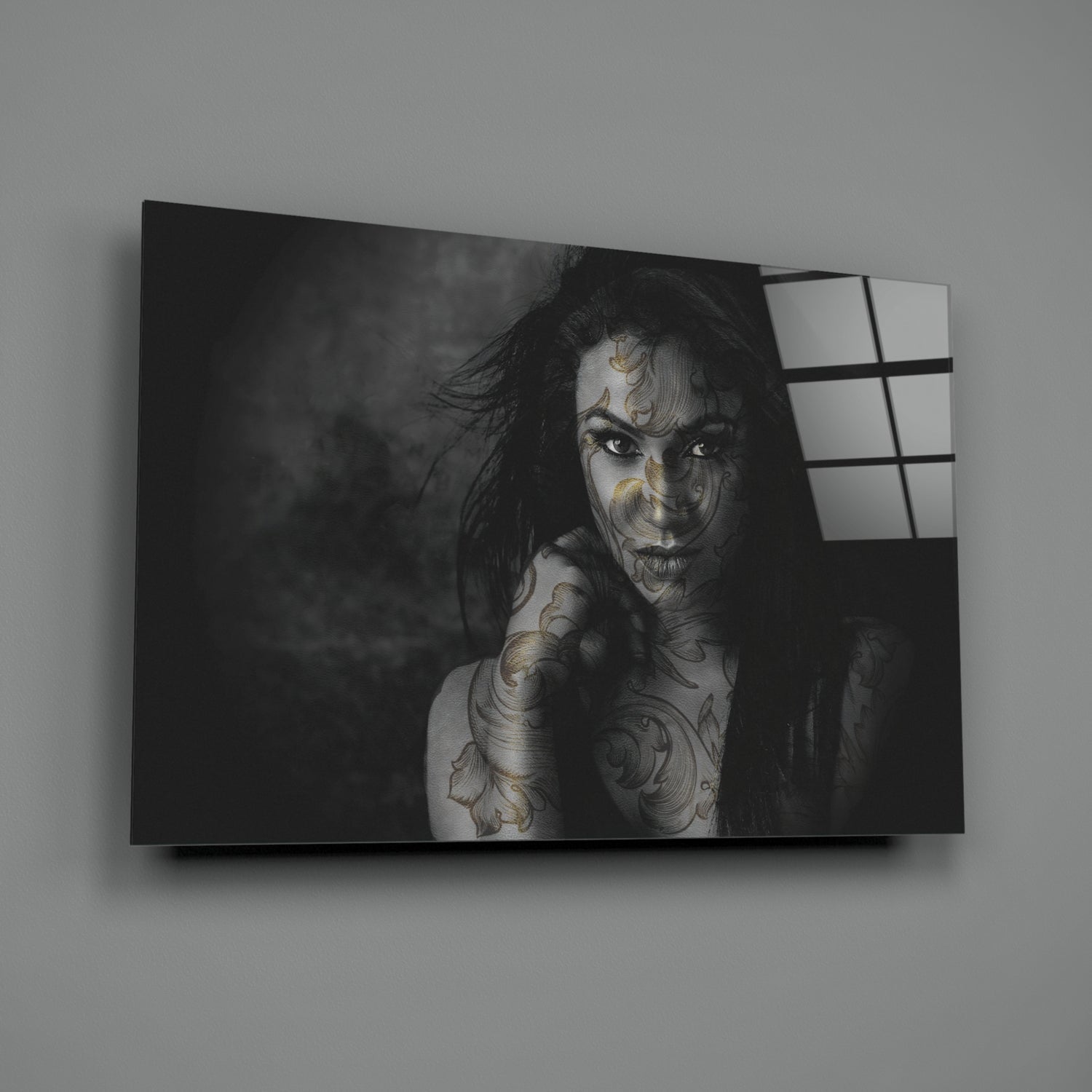 Black and white portrait of tattooed woman on glass wall art panel with window grid reflection on right side.