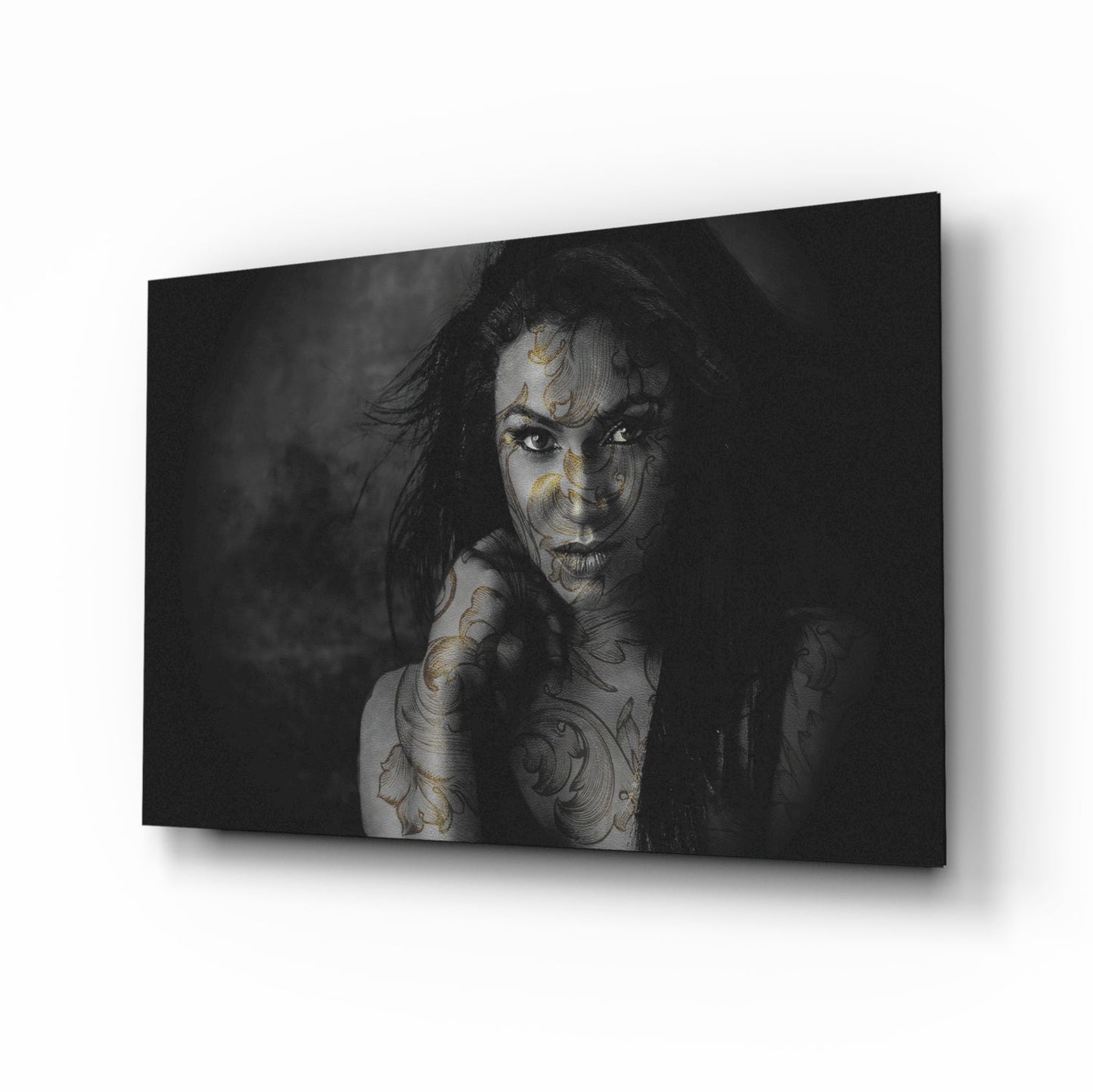 Black and white glass wall art featuring a tattooed woman with ornate body art, displayed at an angled perspective against a white background.