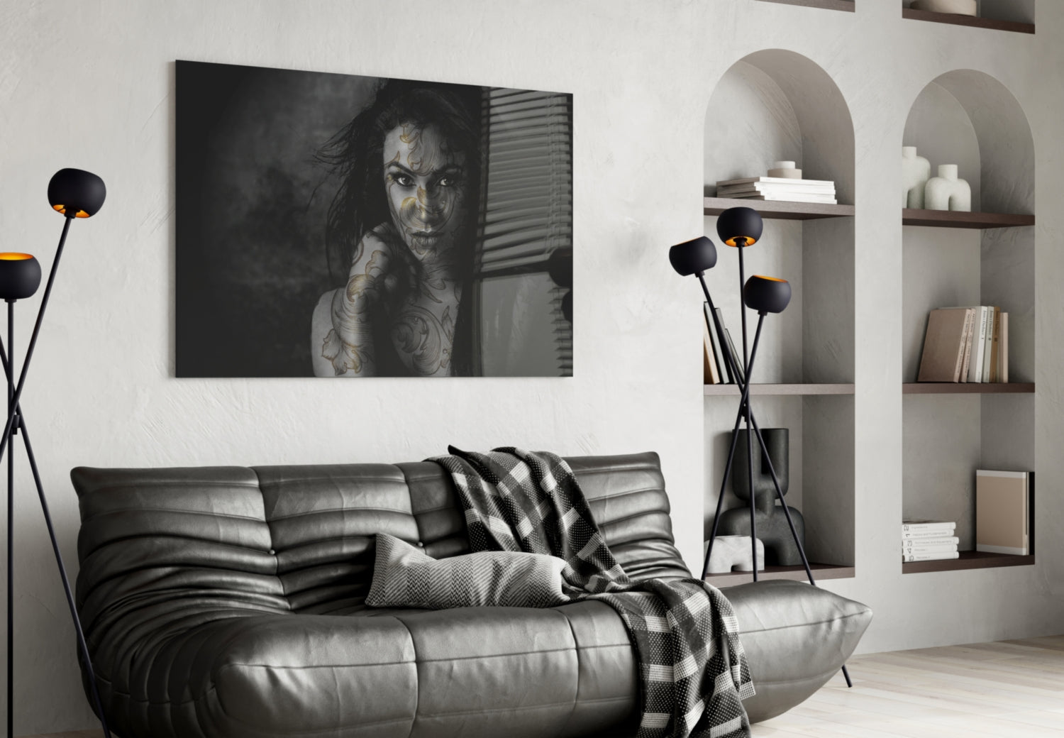 Black and white glass wall art of tattooed woman displayed above leather sofa in modern living room with shelving.