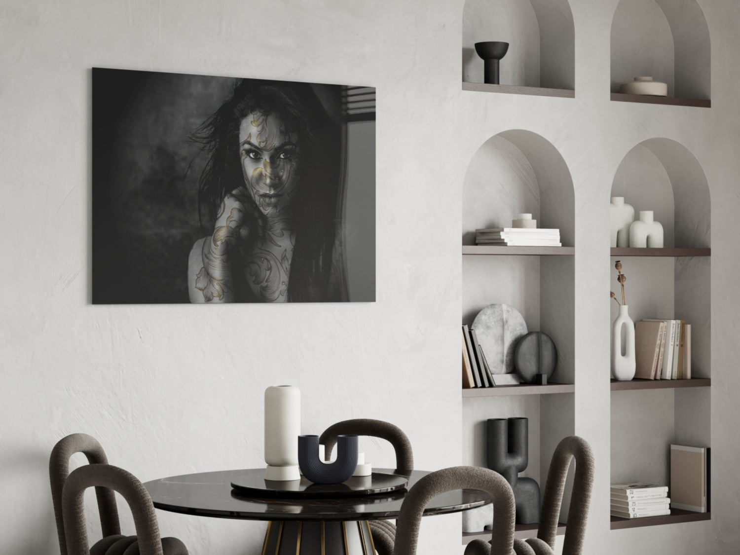 Black and white glass wall art of tattooed woman displayed above round dining table in modern interior setting.