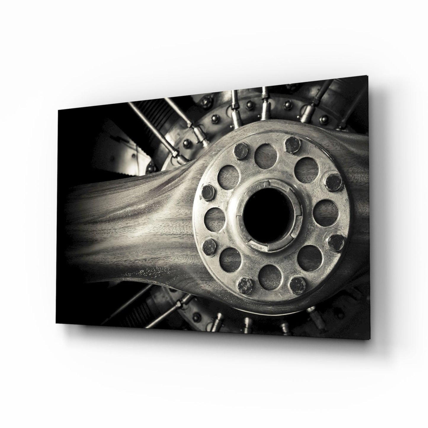 Close-up front view of a metallic wheel hub with multiple bolt holes and central aperture, mounted on wooden spokes against dark mechanical background.
