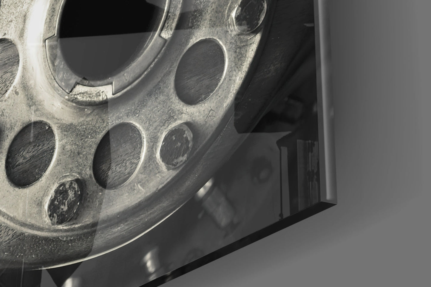 Close-up angled view of a metallic wheel wall art piece with circular cutouts and dust texture against a gray background.