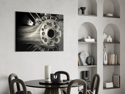Black and white photograph of a motorcycle engine wheel displayed on a white wall above a dining table.