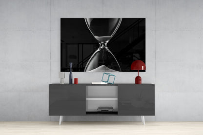 Black and white hourglass artwork displayed above gray media console with red decorative lamp and accessories in modern living room setting.