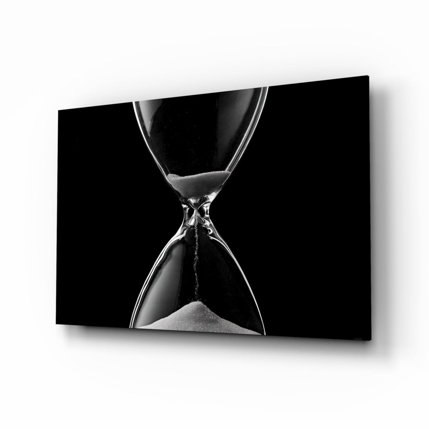 Black and white close-up of an hourglass with flowing sand against a dark background, displayed as framed wall art.