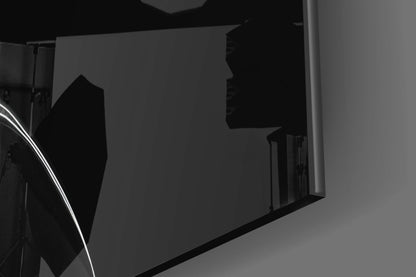 Close-up angled view of black glass hourglass wall art mounted on white wall, showing silhouette profile detail.