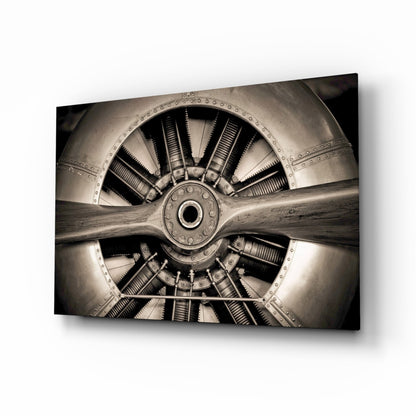 Sepia-toned front view of a radial aircraft engine with nine cylinders, riveted metal cowling, and wooden propeller shaft, displayed as glass wall art.