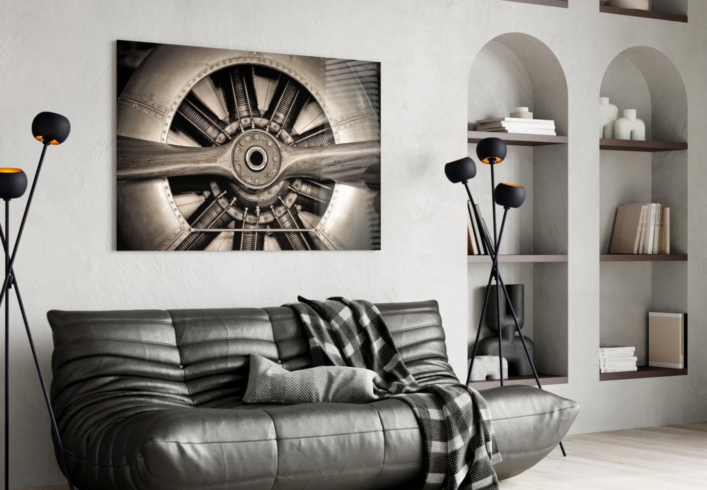 Sepia-toned aircraft propeller glass wall art displayed above a black leather sofa in a modern living room interior.