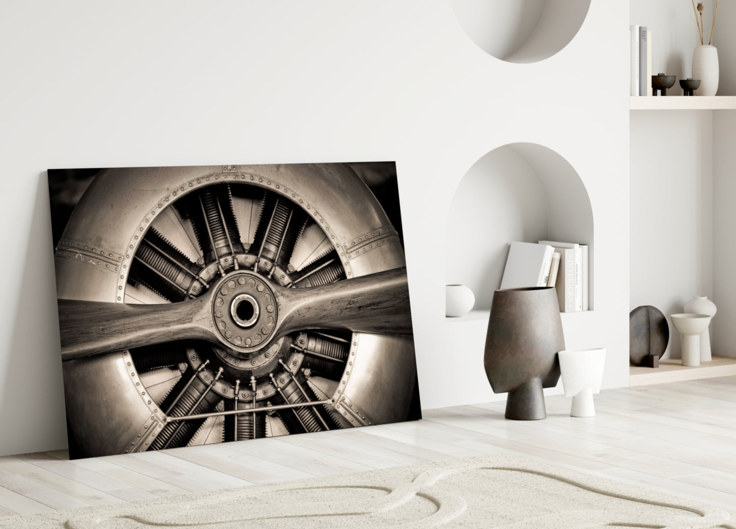 Sepia-toned propeller glass wall art leaning against white wall in minimalist interior with sand and ceramic decor.